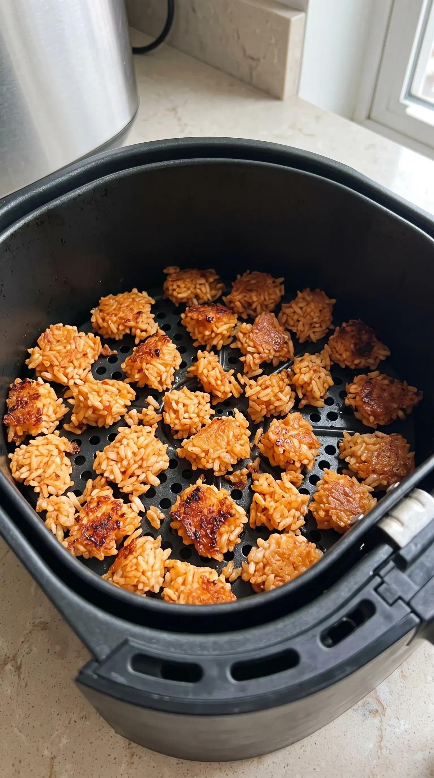 Seasoned jasmine rice pieces crisping in an air fryer basket