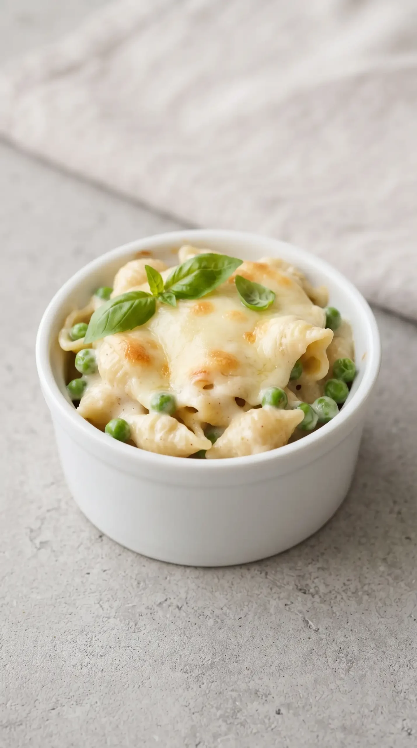 Baked mozzarella pasta with peas and basil in a small ramekin
