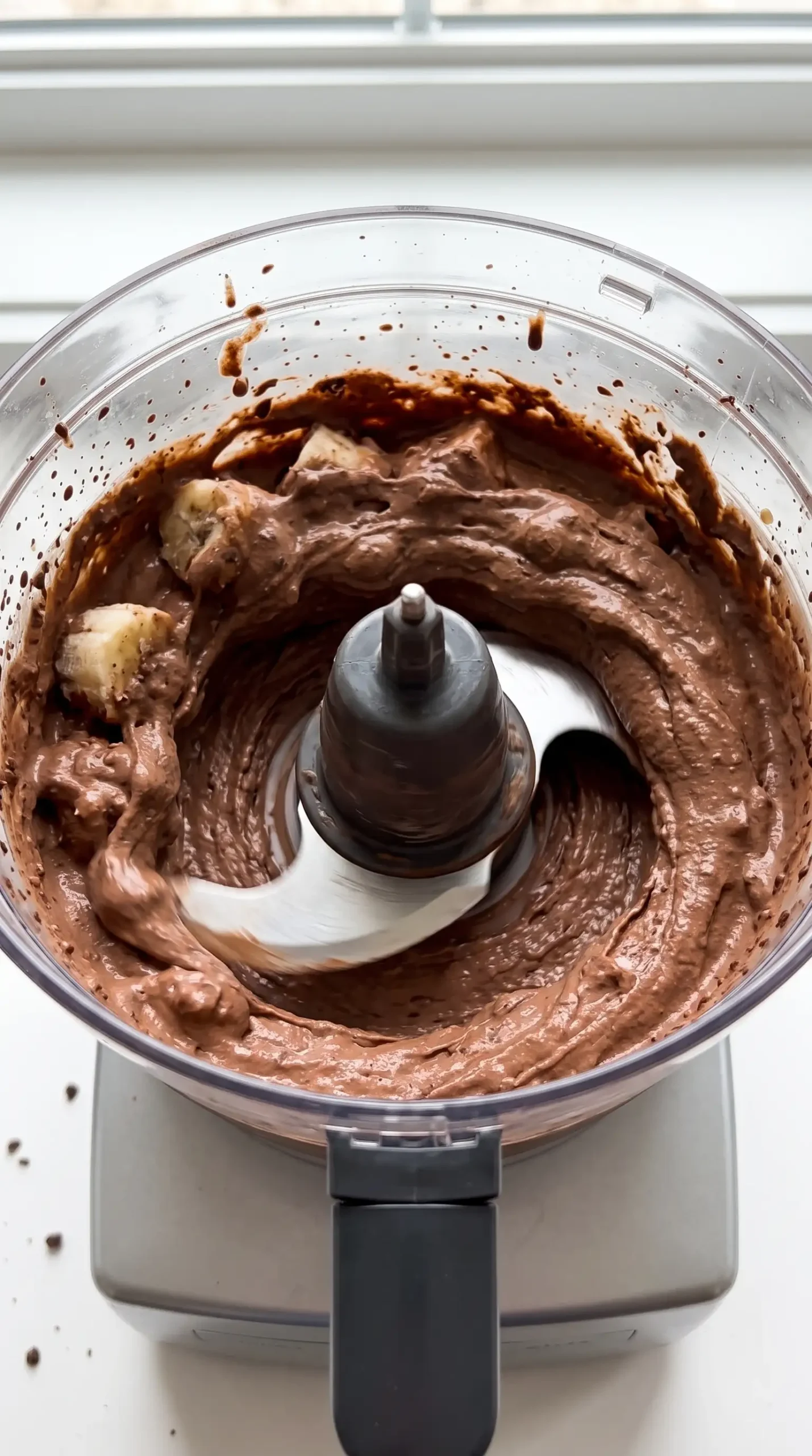 Chocolate banana ice cream mixture blending into a smooth frozen dessert base