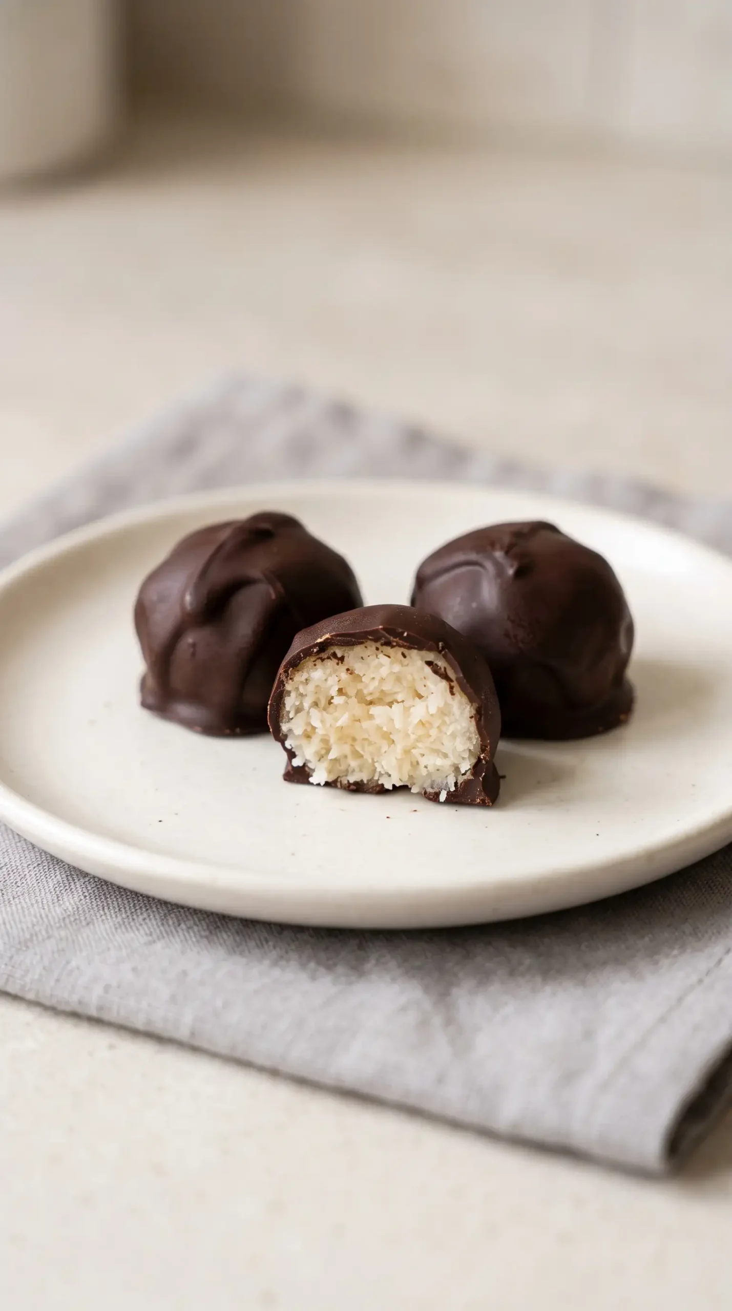 Dark chocolate covered coconut bites served on a ceramic plate