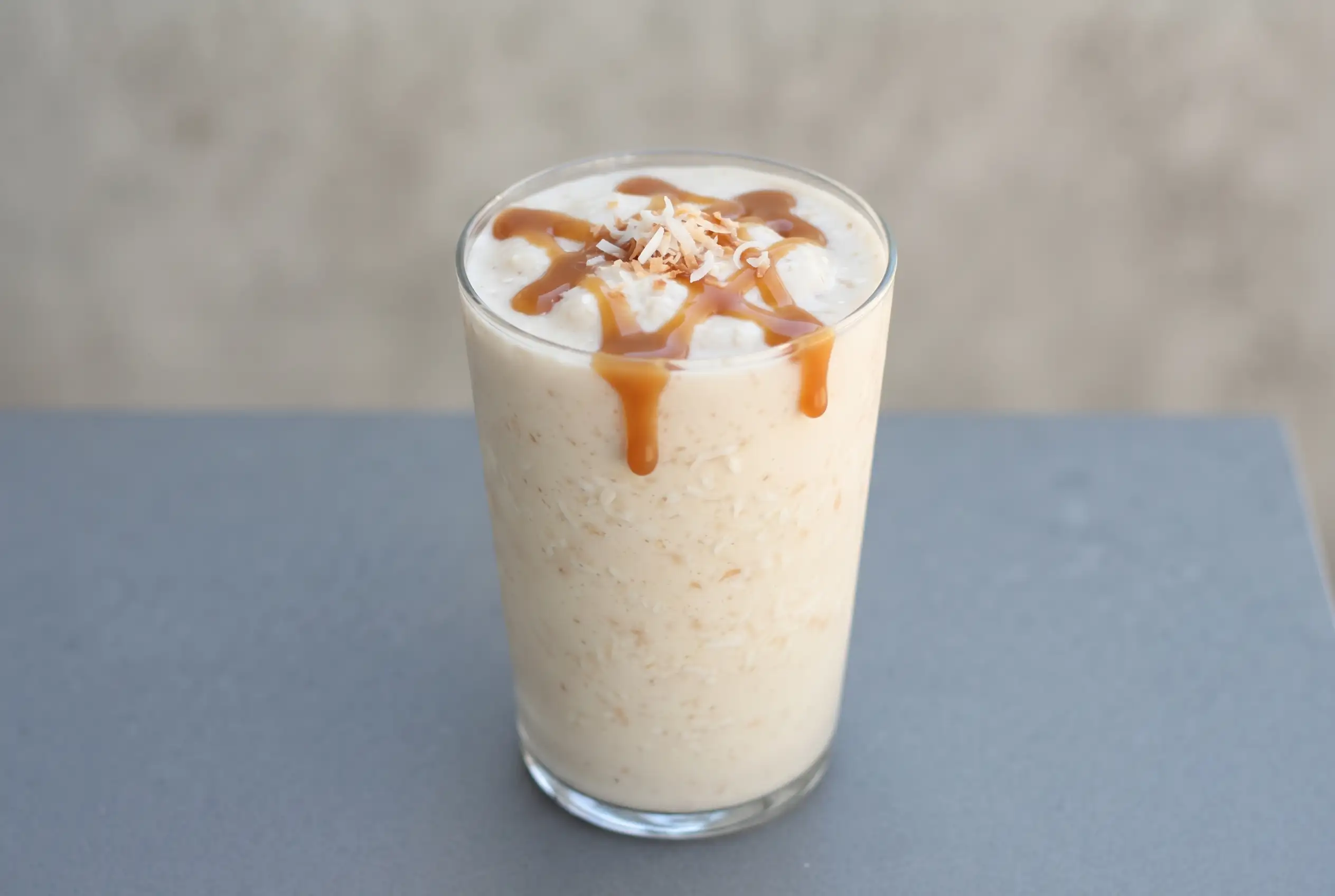 Coconut caramel malt with vanilla bean ice cream, coconut, and caramel drizzle in a tall glass