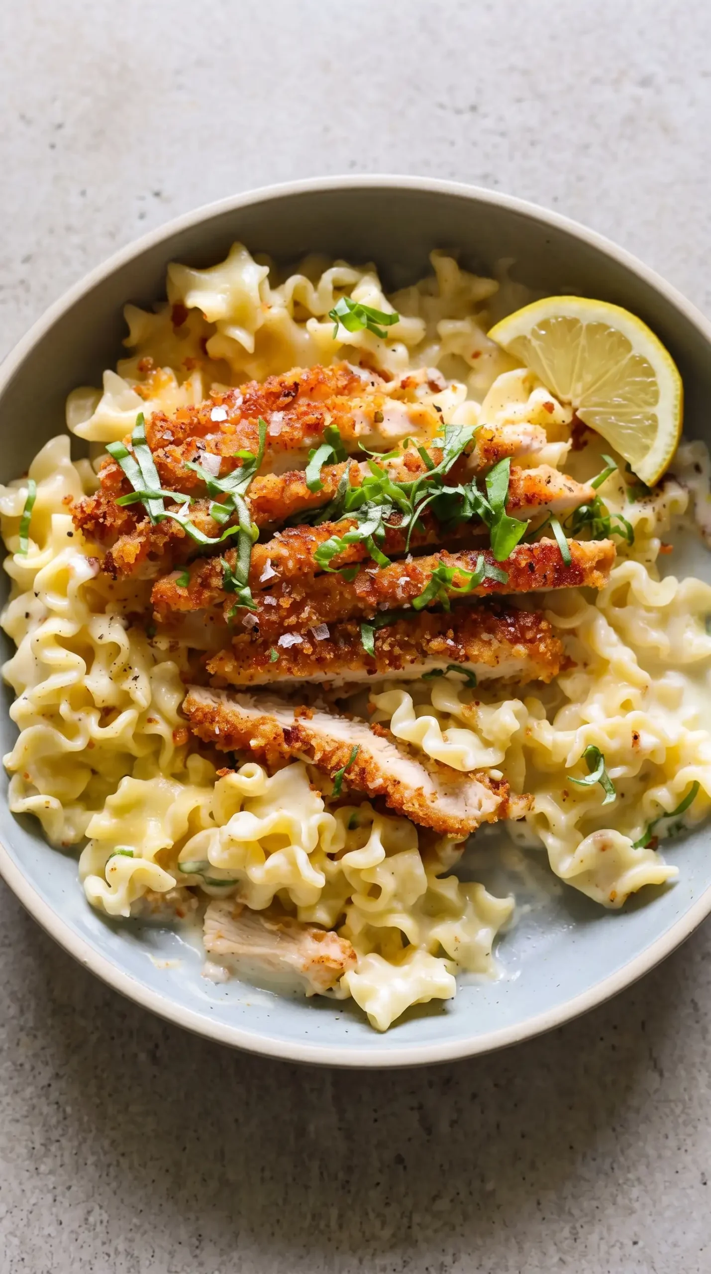 Crispy parmesan chicken served with creamy lemon pasta and fresh basil