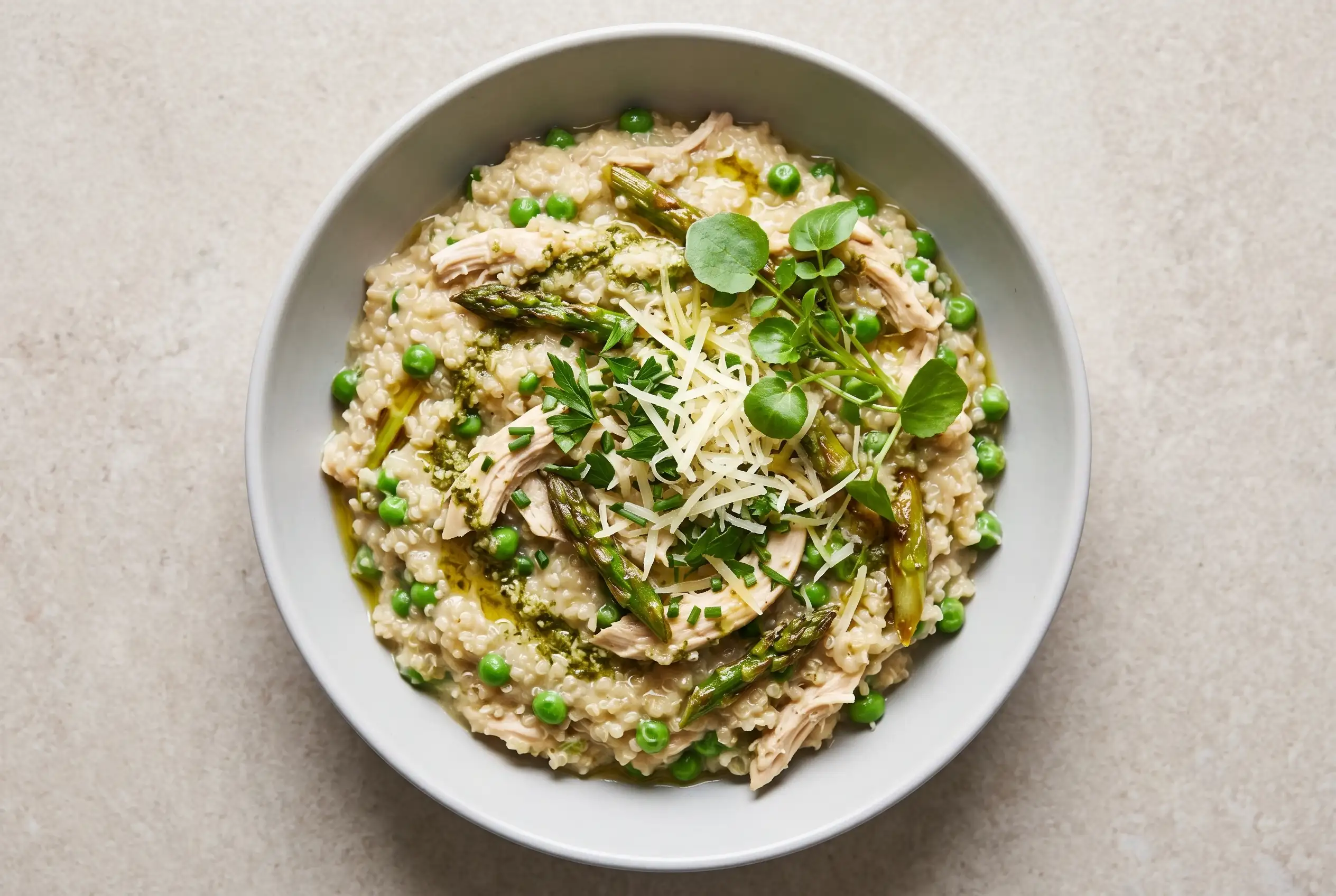 Quinoa chicken primavera bowl with creamy quinoa, shredded chicken, pesto, peas, and asparagus