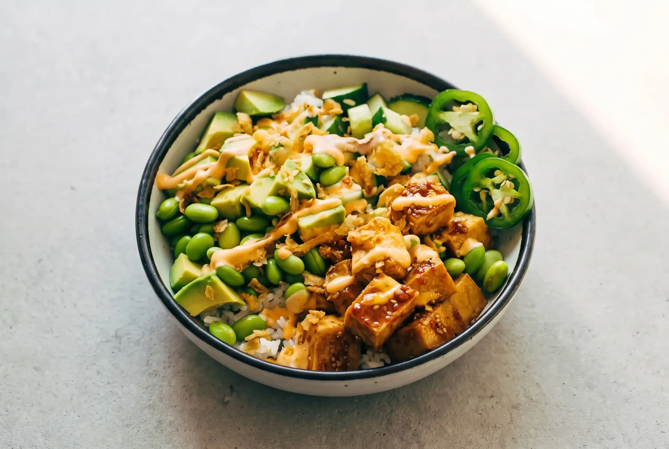 Crunchy roll bowls with crispy tofu, rice, edamame, avocado, cucumber, spicy mayo, and fried onions