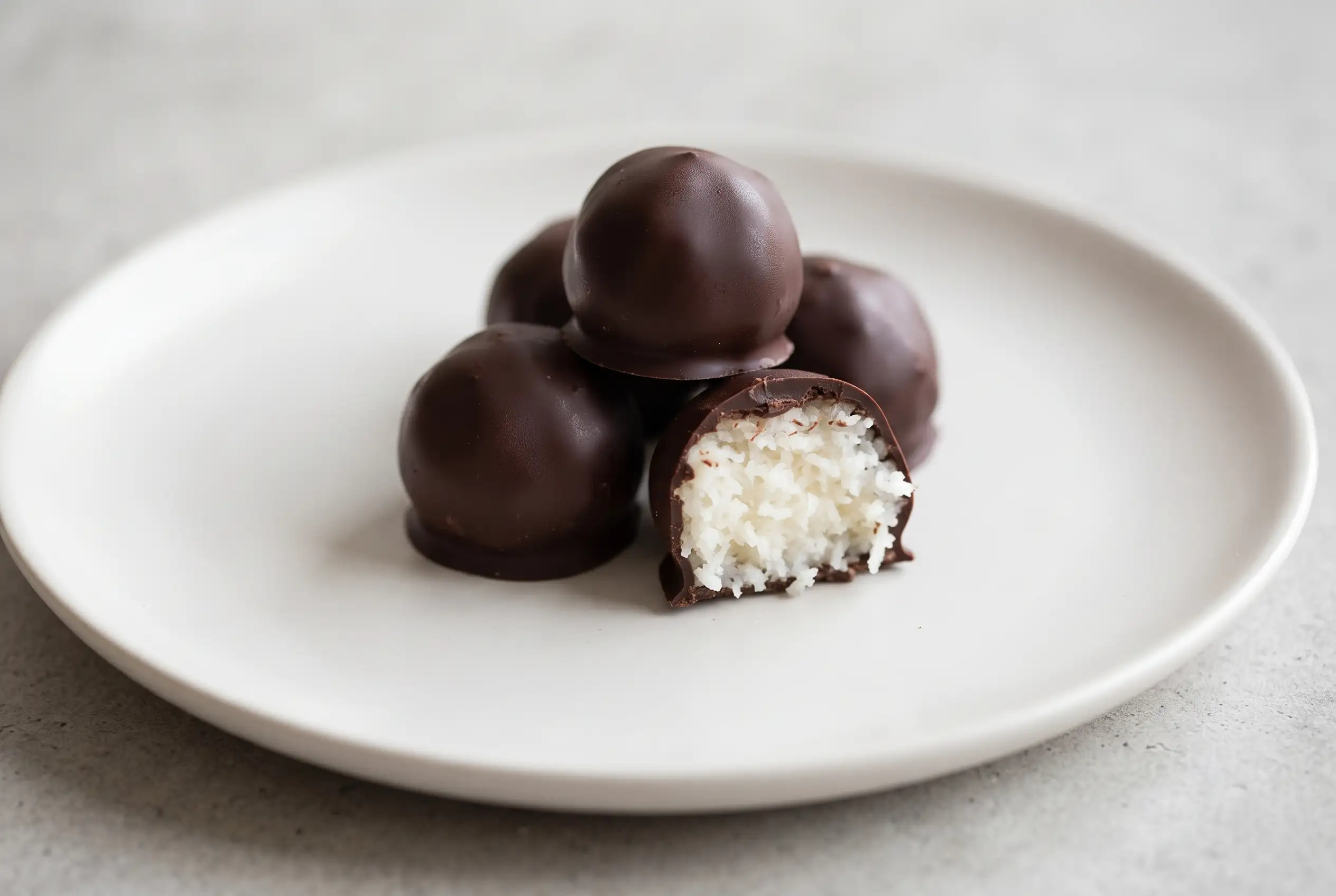 Dark chocolate coconut bites with a glossy chocolate shell and soft coconut center