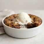 Deep dish cookie with chocolate chips and vanilla ice cream topping in a ramekin