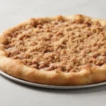 Deep dish cinnamon streusel dessert pizza with maple glaze in a round baking pan