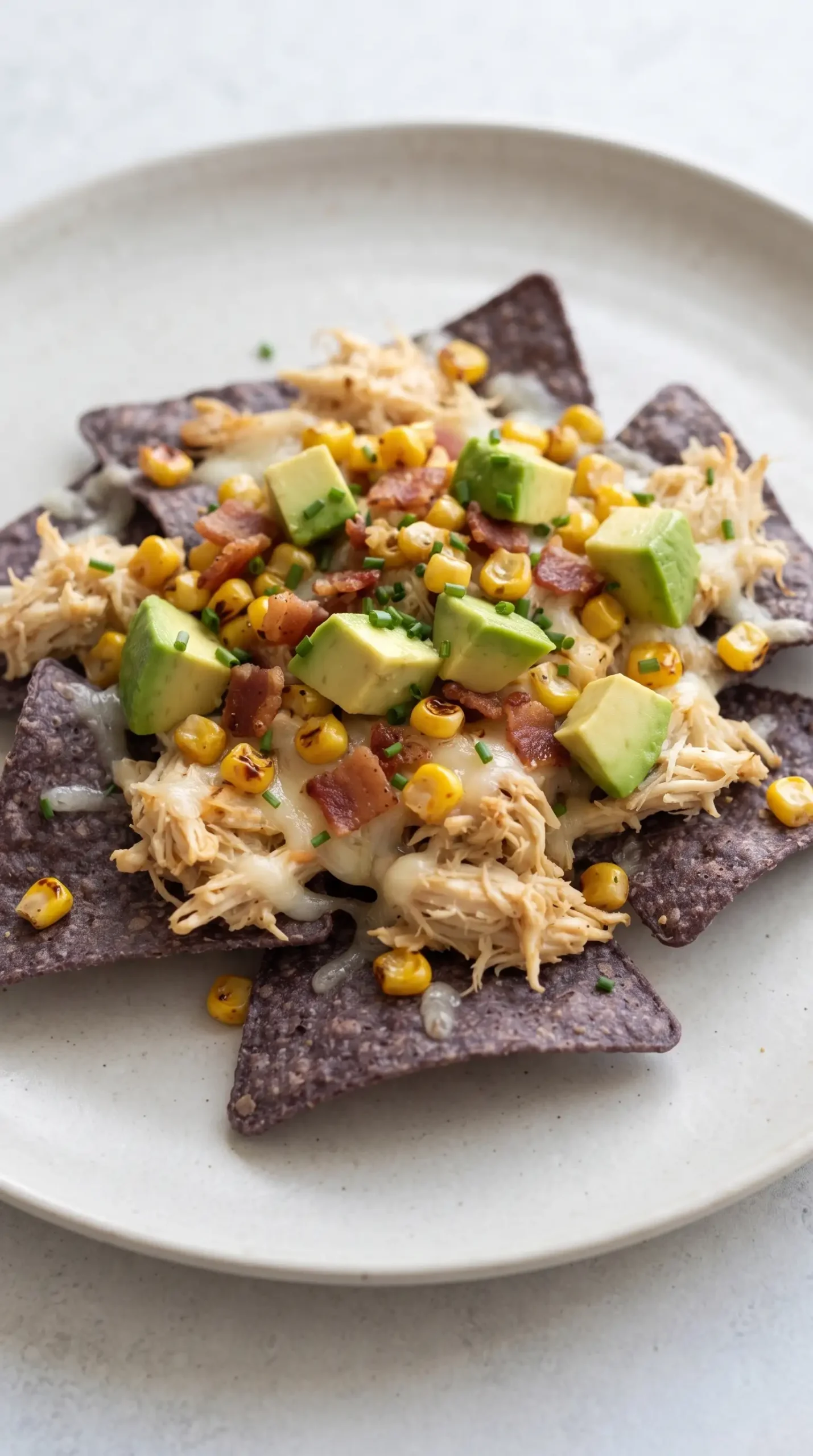 Finished crab and avocado nachos topped with crab, roasted corn, cheese, avocado, and chives