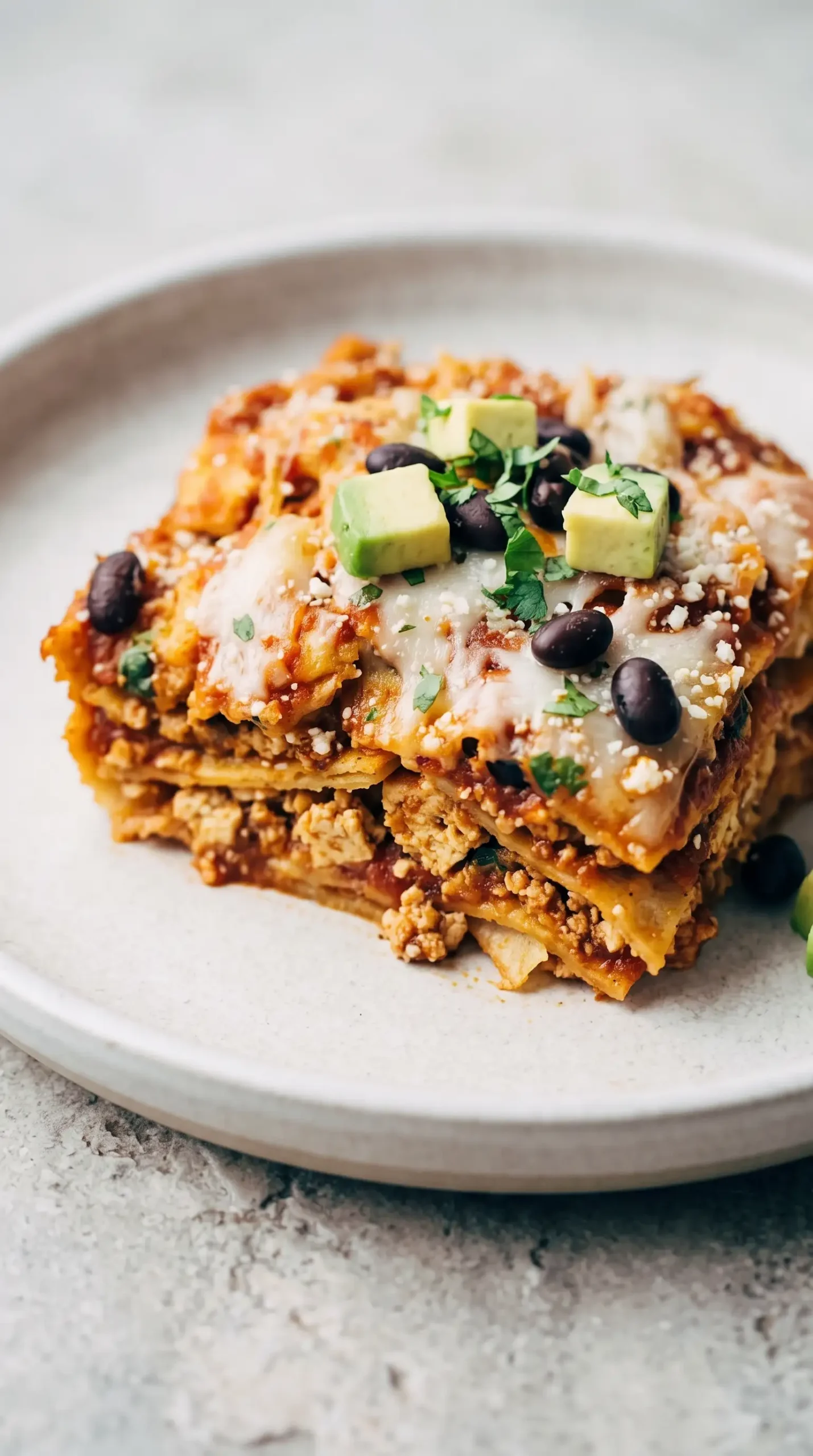 Layered chipotle sofritas casserole serving with tortilla strips, tofu, sauce, and melted cheese