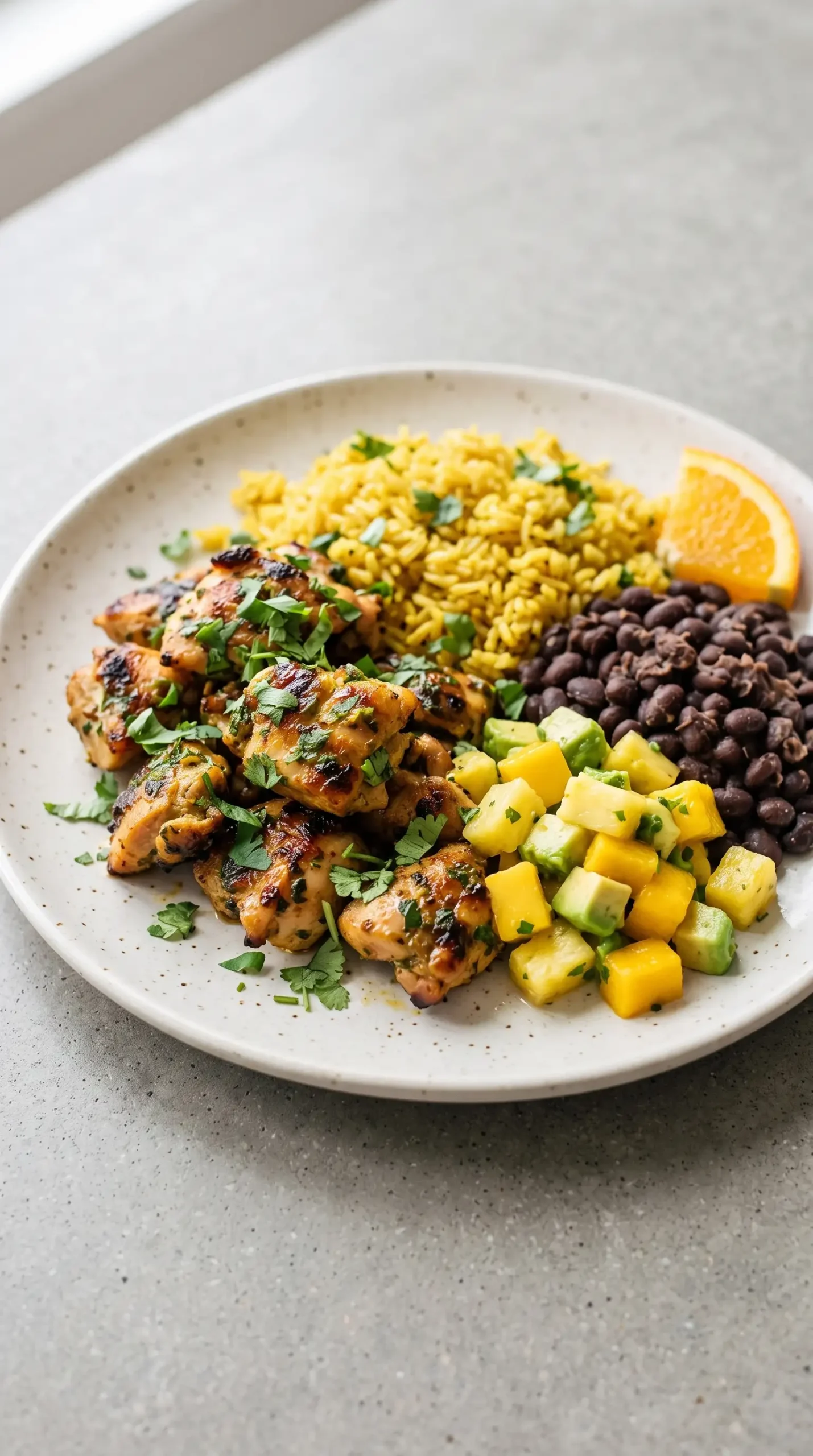 Cilantro orange chicken served with yellow rice, black beans, and fruit salsa