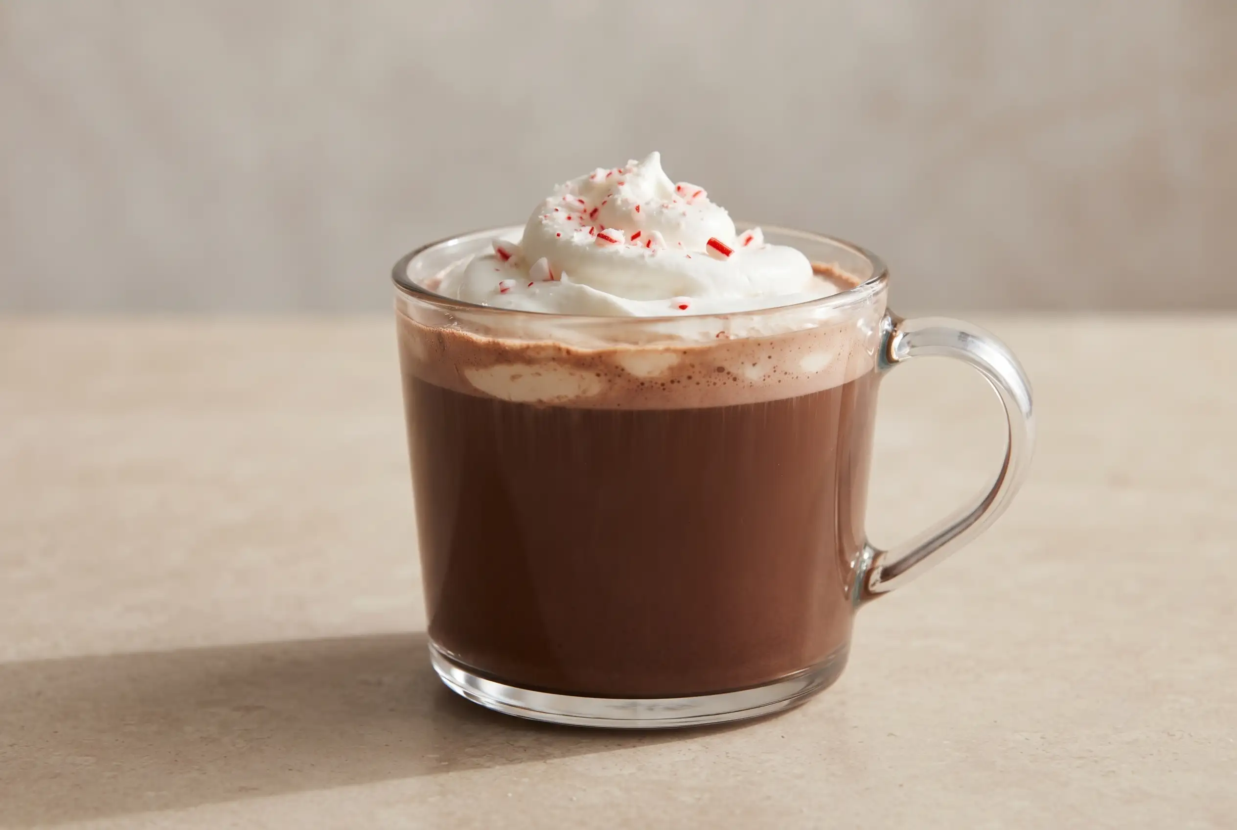 Peppermint mocha with chocolate coffee, whipped cream, and crushed candy cane topping in a glass mug