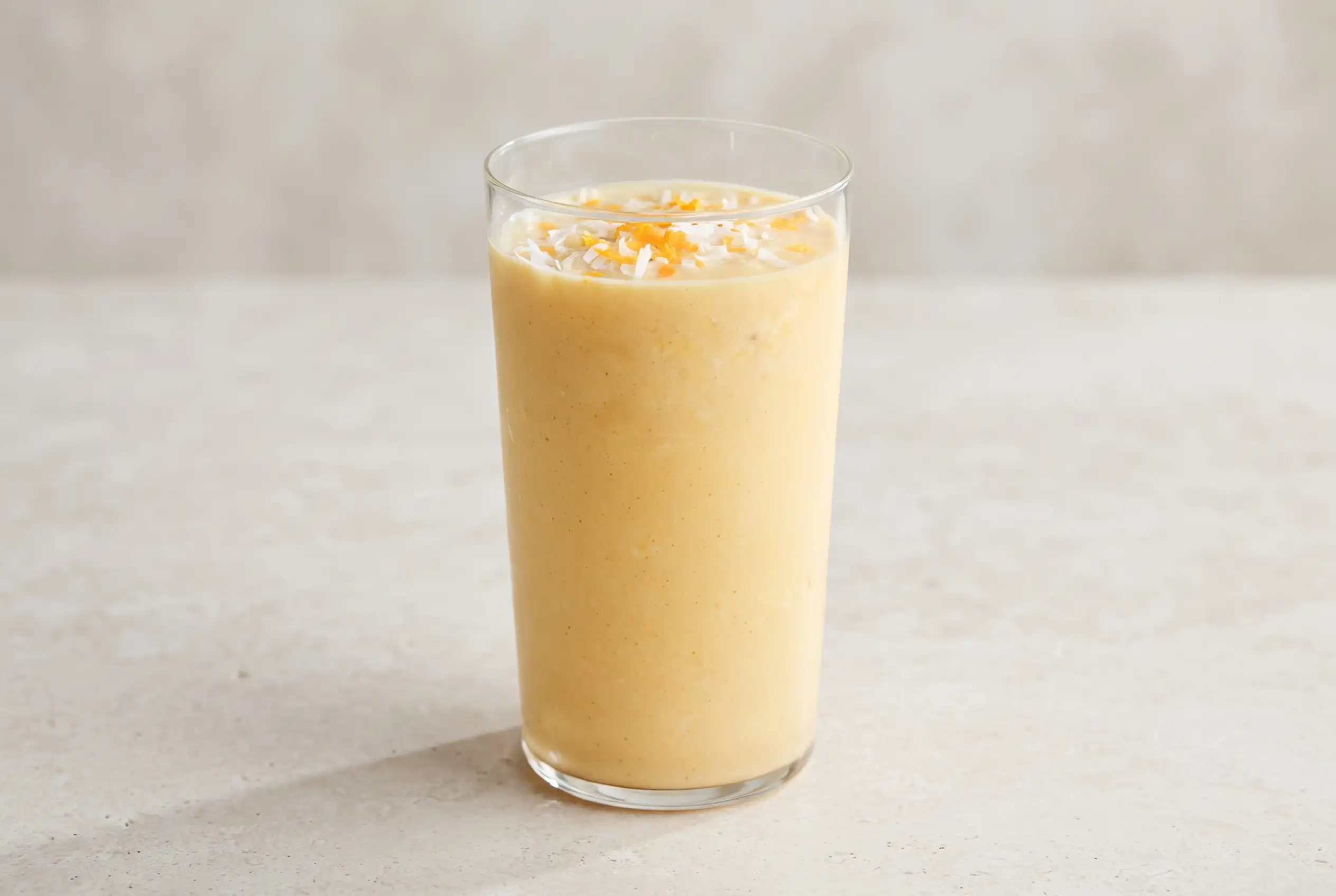 Pineapple orange smoothie in a glass with a creamy tropical blend and coconut garnish