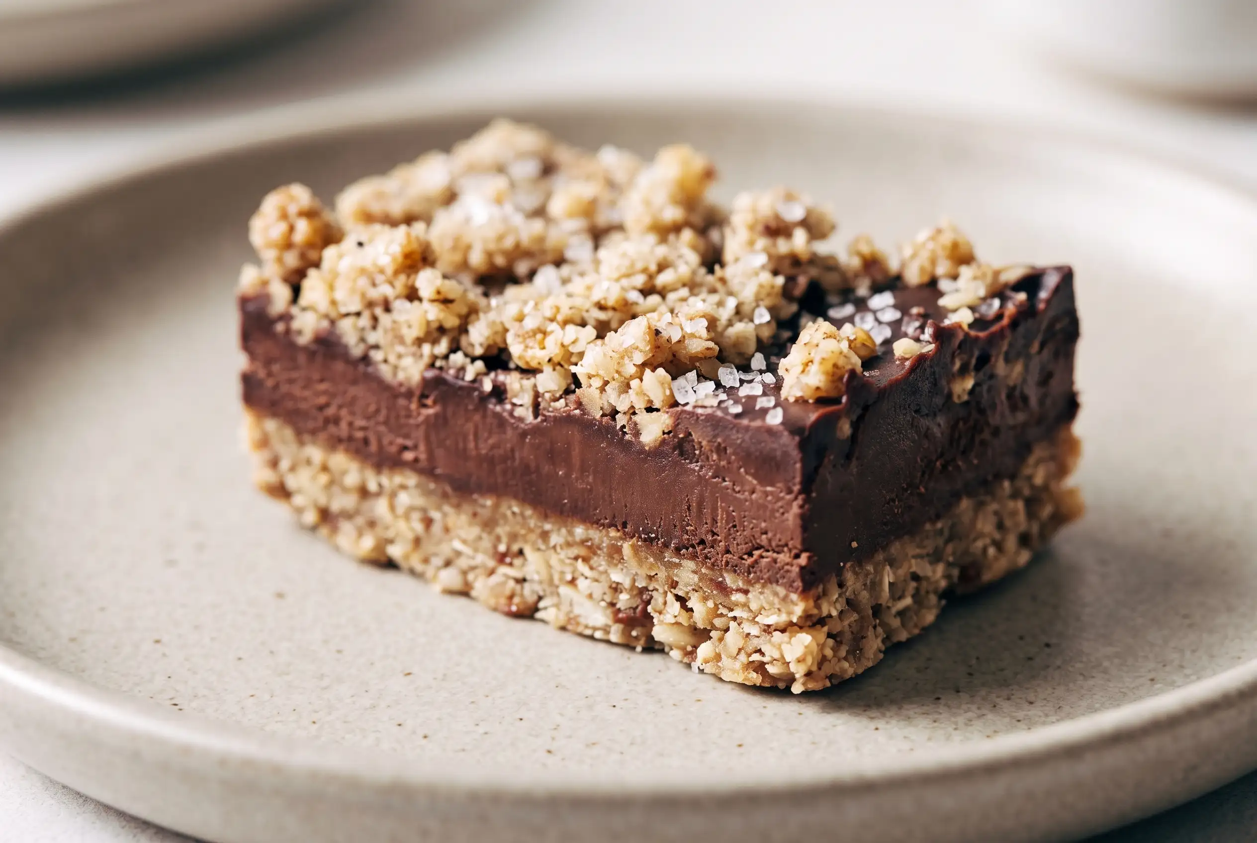 Raw salted chocolate snack bar with pecan oat crust layers and sea salt topping