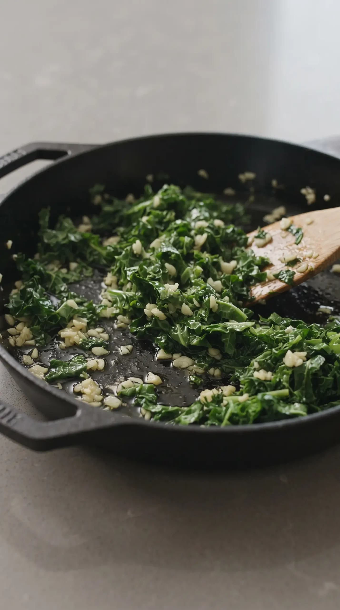 Sautéed kale and garlic cooking in a skillet for pasta